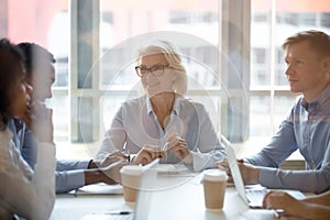 Smiling middle-aged businesswoman hold company office briefing