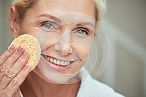 Smiling middle aged caucasian woman with facial sponge