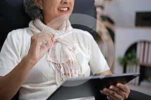 Smiling middle-aged Caucasian woman sit on couch in living room browsing wireless Internet on tablet