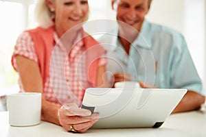 Smiling Middle Aged Couple Looking At Digital Tablet