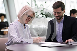 Smiling middle-aged female client sign deal with partner