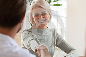 Smiling middle-aged female employee handshake greeting at meeting