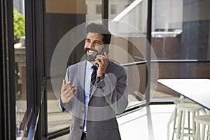 Smiling middle aged Hispanic businessman on phone in office