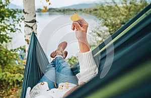 Smiling middle-aged man dressed in warm knitted clothes and jeans lying in the cozy car trunk and enjoying the mountain lake view