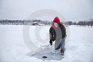 A smiling middle aged man ice fishing on a lake in Minnesota during winter