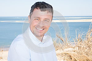 Smiling middle aged man on sea beach coast smiling in summer vacation