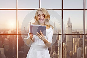 Smiling middle aged mature caucasian blonde lady holding digital tablet.