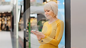 Smiling middle aged mature caucasian woman holding phone looking at smartphone screen sending message checking email