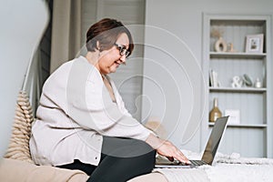 Smiling middle aged plus size woman working on laptop from home