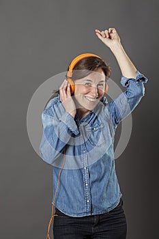 Smiling middle aged woman enjoying dancing and snapping to music