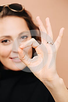 Smiling middle aged woman looking at camera, showing OK gesture.