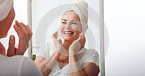 Smiling middle aged woman satisfied with her nature beauty. Cosmetic facial care concept