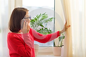 Smiling middle-aged woman is talking on the phone