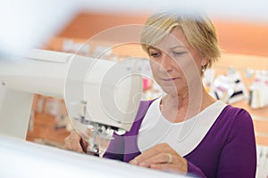 Smiling middle aged woman using sewing machine in laundry