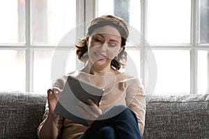 Smiling middle-aged woman using tablet at home