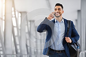 Smiling Middle Eastern Man Talking On Mobile Phone While Walking At Airport
