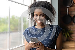 Smiling millennial african ethnicity woman using mobile applications.