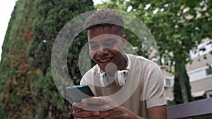 Smiling millennial afro american man having fun watching funny videos on phone