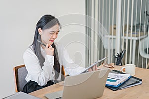 Smiling millennial Asian female office worker working with financial reports for tax audit reports or financial