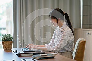 Smiling millennial Asian female office worker working with financial reports for tax audit reports or financial