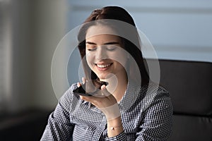 Smiling millennial woman use virtual assistant on cellphone