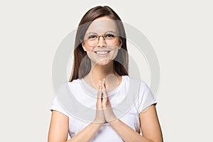 Smiling millennial girl with prayer hands feel thankful