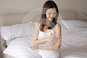 Young woman apply nourishing body cream on arm photo