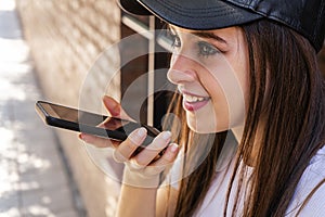 Smiling millennial woman hold modern cellphone talk speak record audio message on gadget, happy young Caucasian woman activate