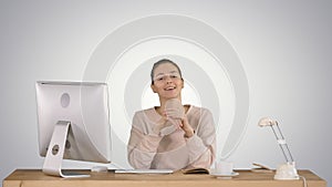 Smiling millennial woman sitting at desk and talking to camera s