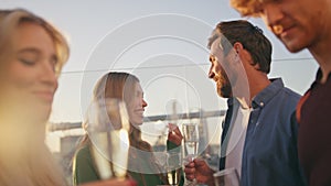 Smiling millennials drinking sparkling wine at rooftop party hangout close up.