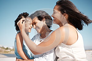 Smiling mixed race family standing together on a beach. Happy hispanic grandmother bonding with granddaughter over a