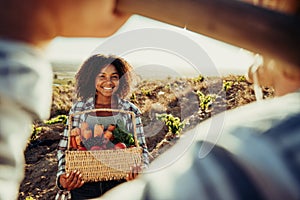 Smiling mixed race female farmer holding fresh vegetables