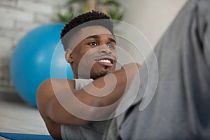 smiling mixed-race man doing sit-ups