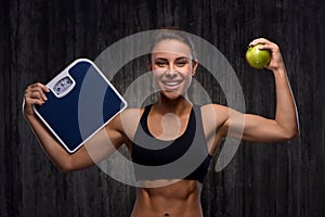 Smiling mixed race sporty woman holding weighs and