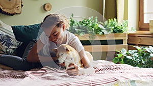 Smiling mixed race teenager is taking selfie with puppy then talking to it and showing it photos on smartphone screen