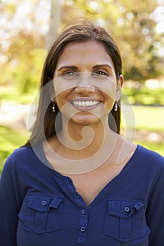 Smiling mixed race woman in park looking to camera, vertical