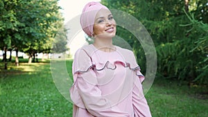 Smiling model in fashionable purple dress and hijab poses