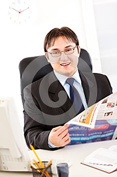 Smiling modern businessman holding newspaper
