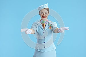 smiling modern female air hostess on blue gesturing