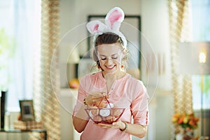 Smiling modern female with basket with eggs for coloring