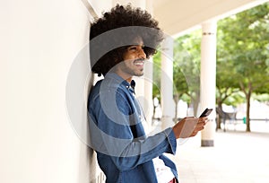 Smiling modern man standing outside with cell phone photo