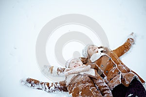 Smiling modern mother and child making snow angel