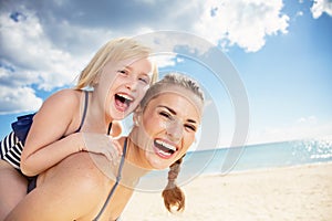 Smiling modern mother and daughter in beachwear on seashore