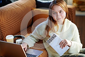 Smiling modern teen girl with laptop and book learning coding