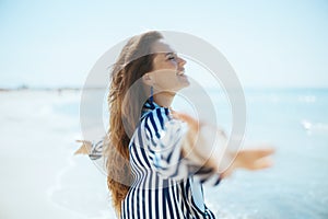 smiling modern woman on beach rejoicing photo