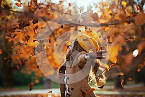 Smiling modern woman in beige coat and orange hat rejoicing