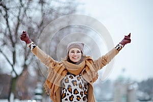 smiling modern woman in brown hat and scarf rejoicing