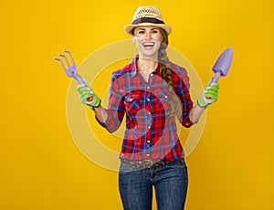 Smiling modern woman farmer showing gardening tools