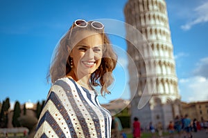 Smiling modern woman in front of leaning tower in Pisa, Italy