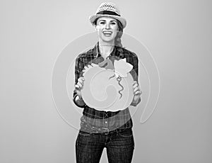 Smiling modern woman grower showing copy space pumpkin